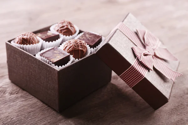 Heerlijke chocolade snoepjes in mooi geschenk vak op houten achtergrond — Stockfoto