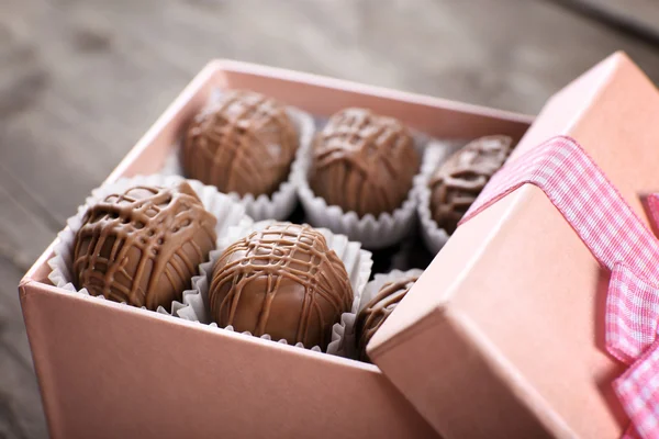 Sabrosos caramelos de chocolate en caja de regalo rosa sobre fondo de madera, de cerca — Foto de Stock