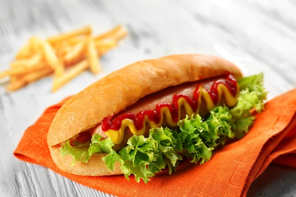 Délicieux hot-dog aux frites et légumes sur table en bois — Photo