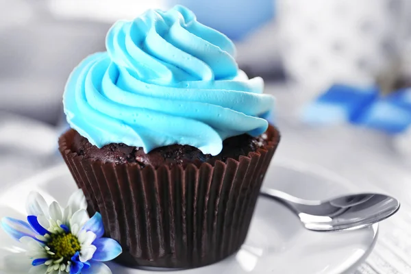 Heerlijke chocolade cupcake met blauwe crème op versierde houten tafel, close-up — Stockfoto