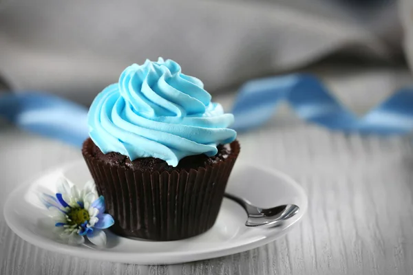 Läcker choklad cupcake med blå grädde på inredda träbord, närbild — Stockfoto