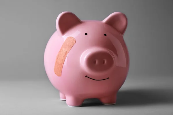 Piggy Bank Leukoplaszt szürke háttér — Stock Fotó