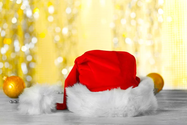 Sombrero rojo de Santa Claus con decoraciones navideñas en la nieve artificial sobre fondo brillante, primer plano —  Fotos de Stock