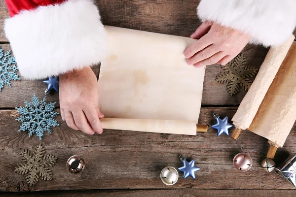 A list of Christmas wishes in Santa Claus hands on wooden background