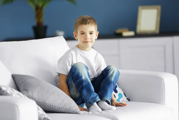Mały chłopiec siedzi na kanapie — Zdjęcie stockowe