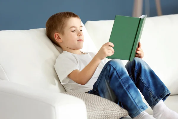 Menino lendo livro em um sofá — Fotografia de Stock