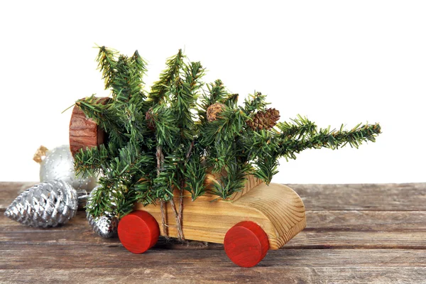 Carro de brinquedo de madeira com árvore de Natal e brinquedos em uma mesa sobre fundo branco — Fotografia de Stock