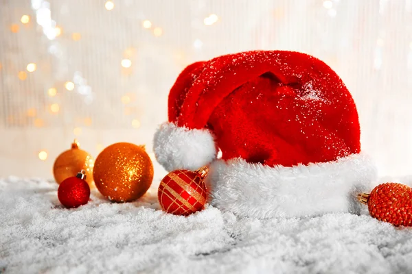 Chapeau de Père Noël avec des jouets sur une table enneigée sur fond de paillettes — Photo