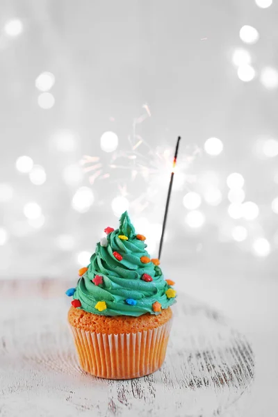 Kerstmis cupcake met sparkler en lichten op achtergrond — Stockfoto