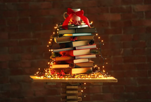 Árvore de Natal feita de livros na mesa no fundo da parede de tijolo — Fotografia de Stock