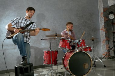 Bateri ve gitar çalmaya müzisyenler
