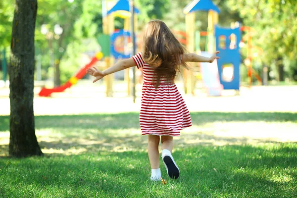 Lite glad flicka som leker i parken — Stockfoto