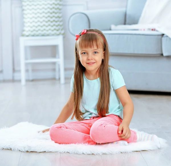 Pequena menina bonito sentado no tapete — Fotografia de Stock