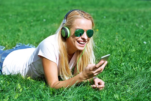 Vrouw met oortelefoons en smartphone — Stockfoto