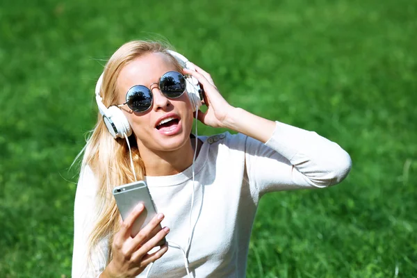 Vrouw met oortelefoons en smartphone — Stockfoto