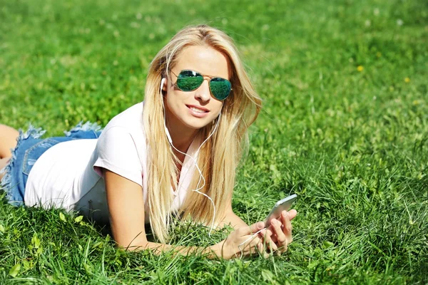 Kvinna med hörlurar och smartphone — Stockfoto