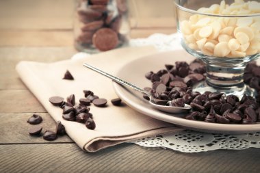 Ahşap arka plan üzerinde cam kase çikolata morsels