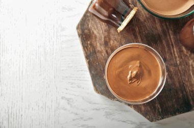 Ahşap arka plan üzerinde cam kapta eritilmiş çikolata