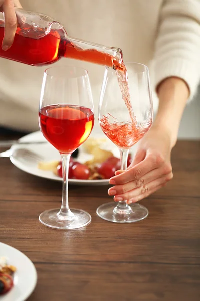 Giovane donna versando il vino rosa nel bicchiere sul tavolo — Foto Stock