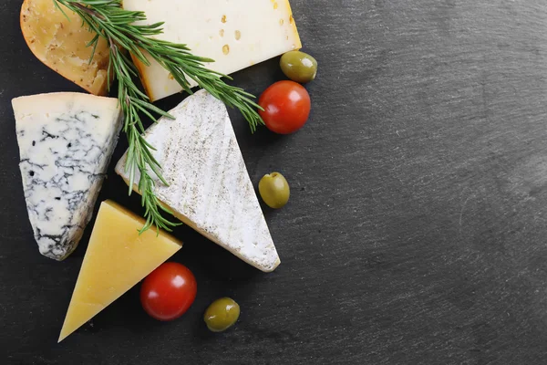 Verschillende soorten kaas, tomaten en olijven op zwarte bord, kopiëren ruimte — Stockfoto