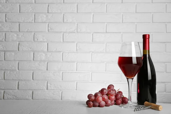 Rotwein und Trauben auf Backsteinmauer Hintergrund — Stockfoto