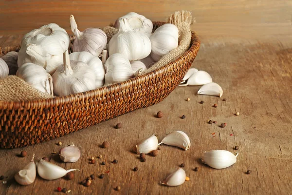 Garlic in wicker bowl on wooden background — Stock Photo, Image