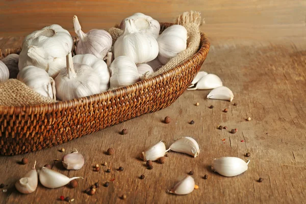 Knoflook in rieten kom op houten achtergrond — Stockfoto