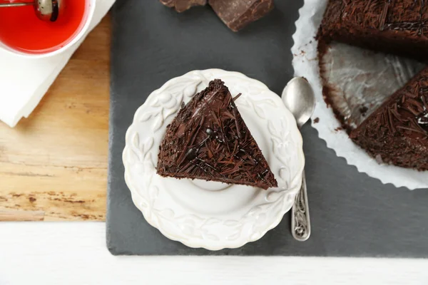 Sliced chocolate cake on wooden table, on light background — Stock Photo, Image