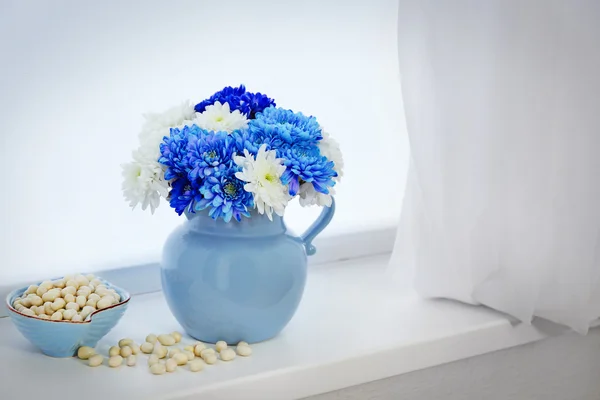 Jar with flowers on windowsill — Stock Photo, Image