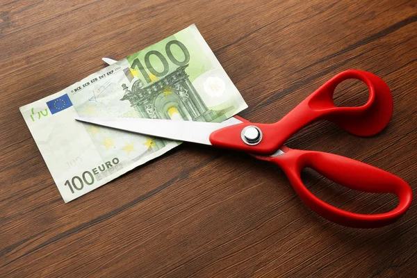 Red scissors cut money