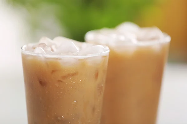 Cups of ice coffee on light blurred background — Stock Photo, Image