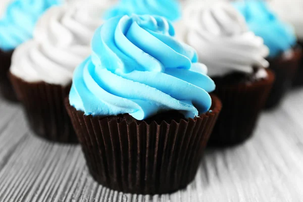 Fresh delicious cupcakes in a row on white wooden  background — Stock Photo, Image