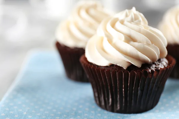 Delicious chocolate cupcakes with cream on served table, close up — Stock Photo, Image