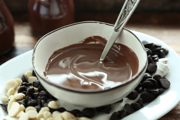 Kase, ahşap arka plan üzerinde eritilmiş çikolata — Stok fotoğraf