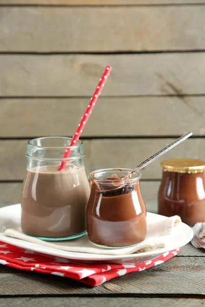 Шоколадный десерт в маленькой стеклянной банке и шоколадный молочный коктейль на деревянном фоне — стоковое фото