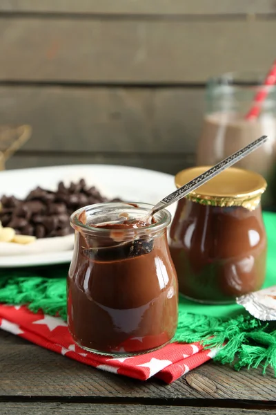 Sobremesa de chocolate em um pequeno jarro de vidro e coquetel de leite de chocolate no fundo de madeira — Fotografia de Stock