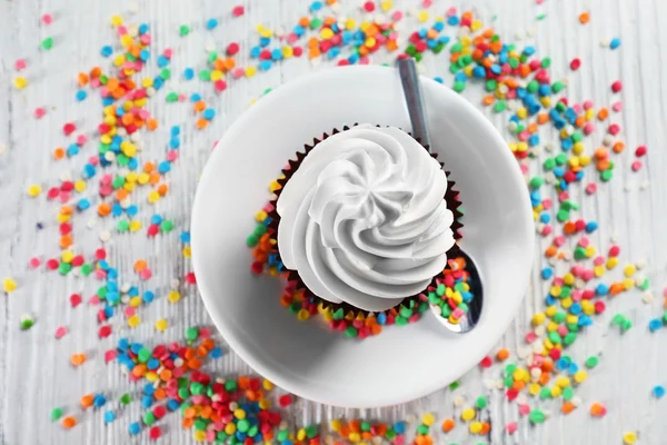 Delizioso cupcake al cioccolato decorato con dolciumi colorati sul tavolo servito, primo piano — Foto Stock