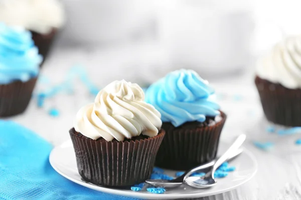 Bolinhos de chocolate com creme colorido na mesa servida, close-up — Fotografia de Stock