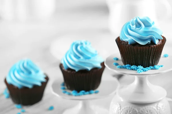 Deliciosos cupcakes de chocolate con crema azul en una fila en la mesa de madera decorada, de cerca —  Fotos de Stock