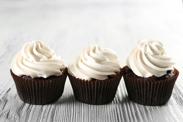 Cupcakes saborosos no fundo de madeira branco, close-up — Fotografia de Stock
