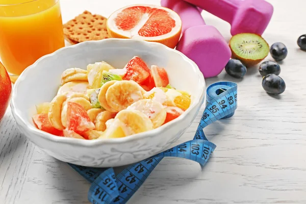 Ensalada de frutas y mancuernas sobre fondo de madera. Concepto de alimentación saludable . —  Fotos de Stock