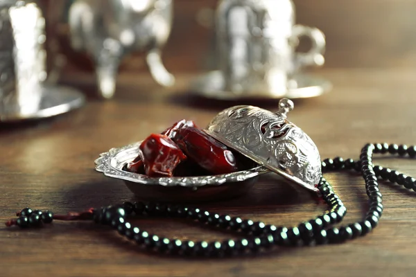 Dates fruit and rosary on served wooden background, close up — Stock Photo, Image