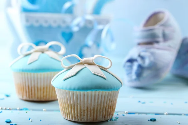 Tasty cupcake with bow and baby shoes — Stock Photo, Image