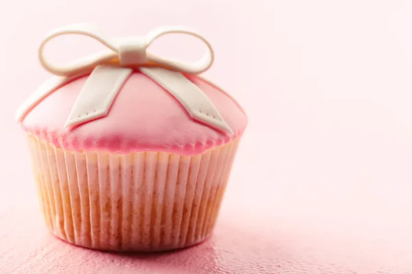 Sabroso cupcake con lazo sobre fondo de madera de color — Foto de Stock