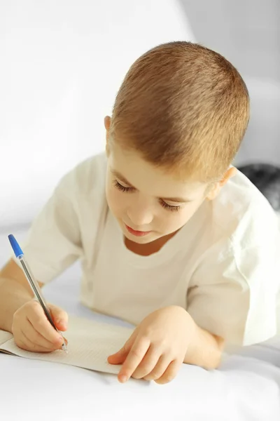 Kleiner Junge schreibt in Notizbuch — Stockfoto