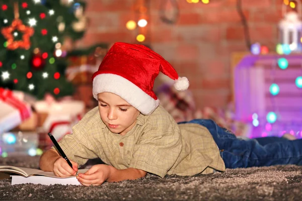 Jongen schrijven in notitieblok op een kerstfeest — Stockfoto