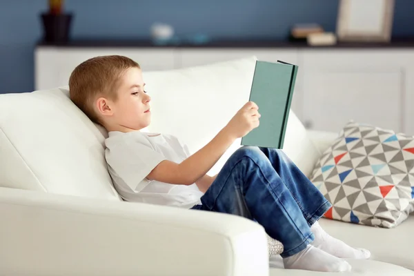 Menino lendo livro em um sofá — Fotografia de Stock