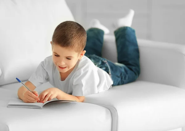 Kleiner Junge schreibt in Notizbuch — Stockfoto