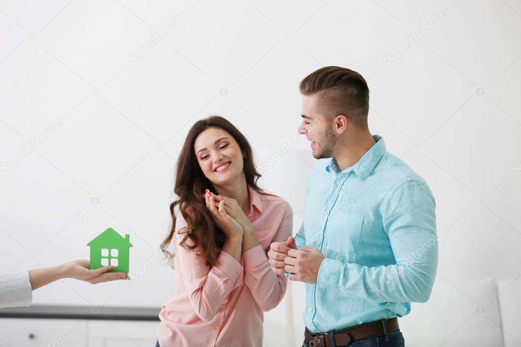 realtor giving model of house to couple