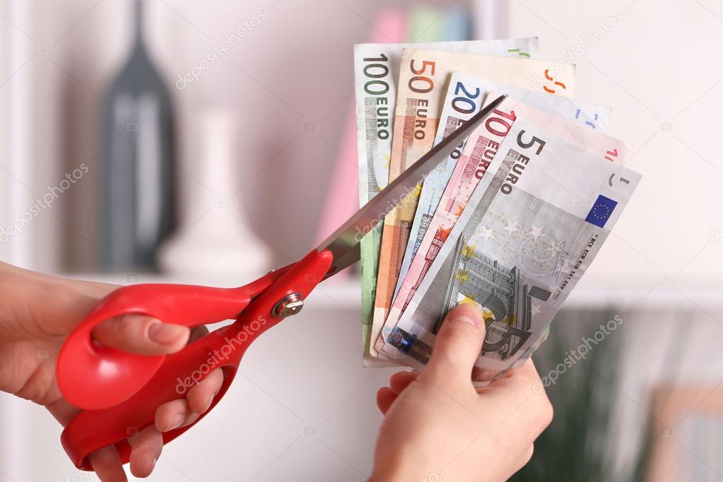 Hands with scissors cutting Euro